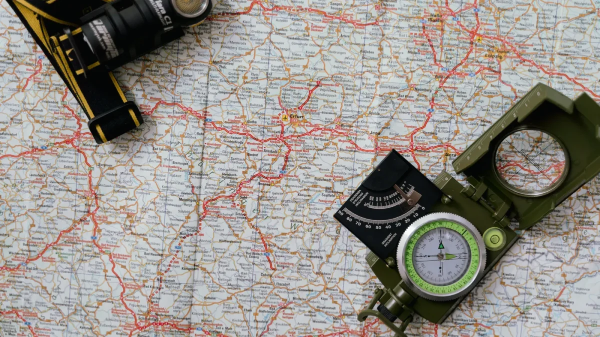 Overhead view of a paper map with a compass and a headlamp