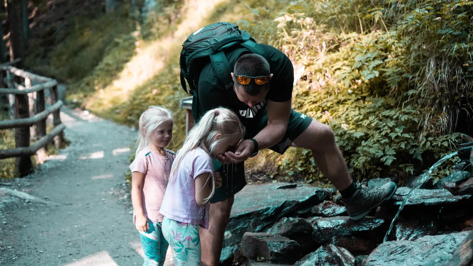 Father exploring a forest path with two young daughters