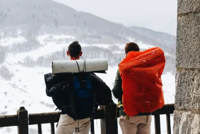 Two hikers with large backpacks looking at a snowy mountain view in winter