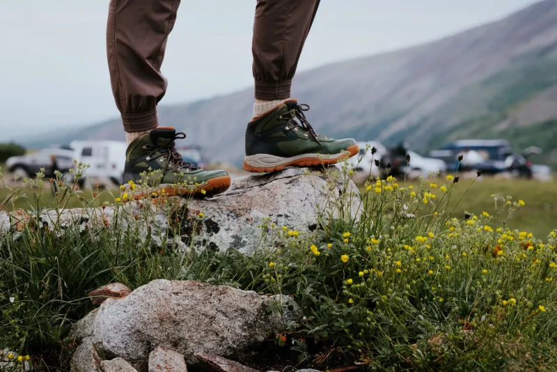 Hiker's boots on a rocky outcrop above a wildflower valley in Alma, Colorado