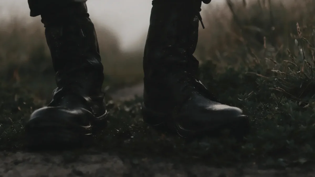 Close-up of black military boots standing on a rugged dirt path