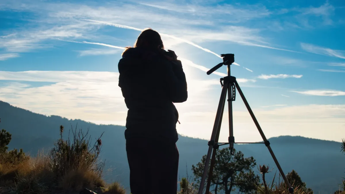 Photographer setting up a tripod to capture a mountain sunrise