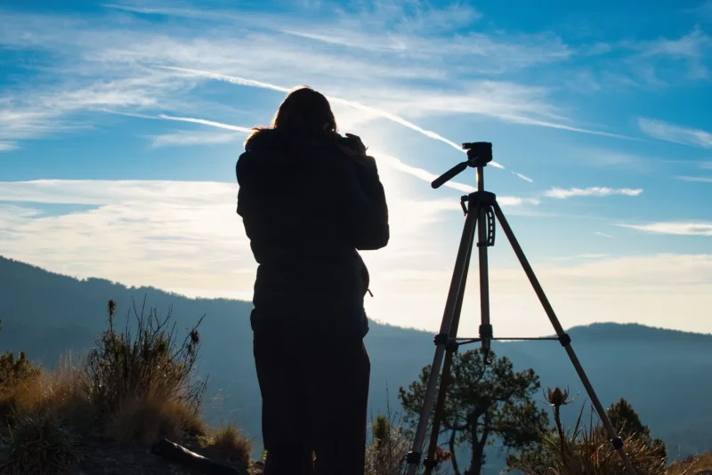 Photographer setting up a tripod to capture a mountain sunrise