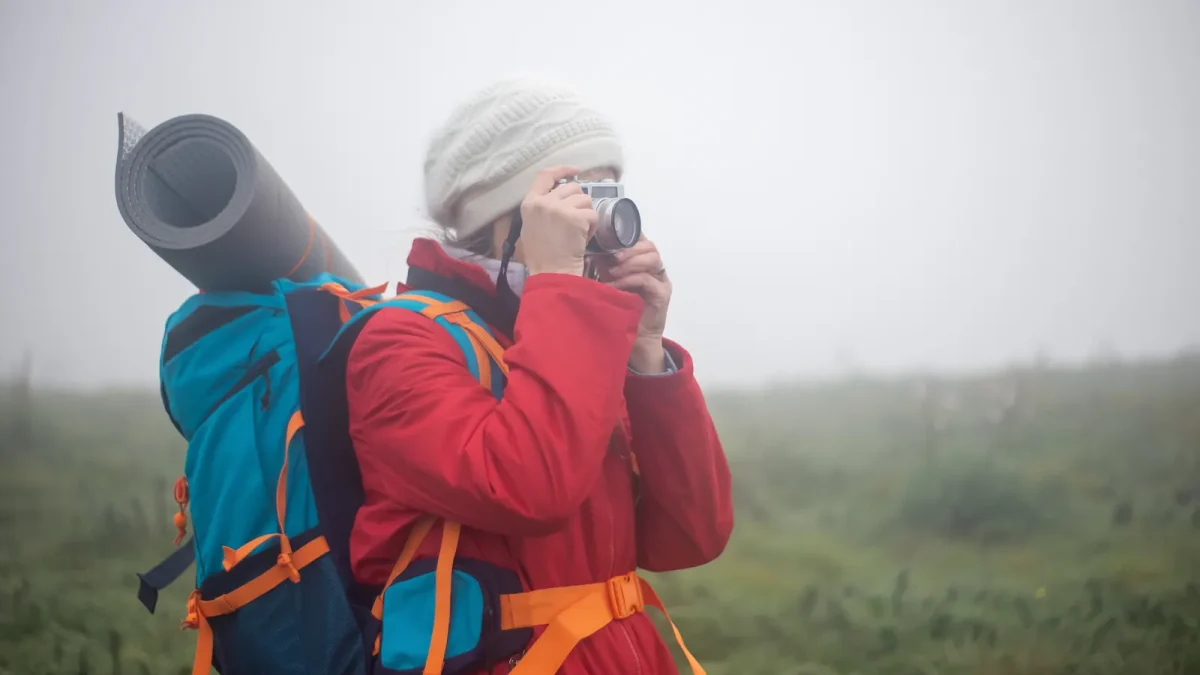 Woman photographer using a camera on a misty hiking trail