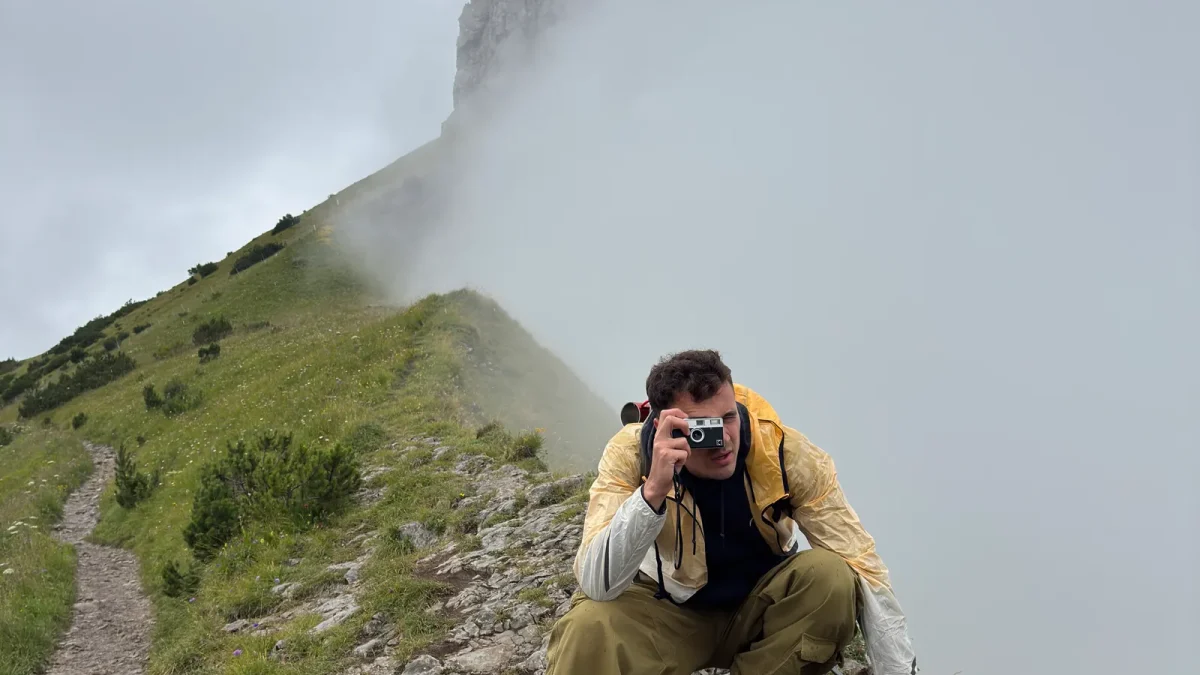 Photographer on a foggy mountain ridge using a camera