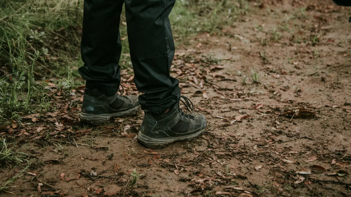 Close-up of a hiker's legs in dark hiking pants on a forest trail