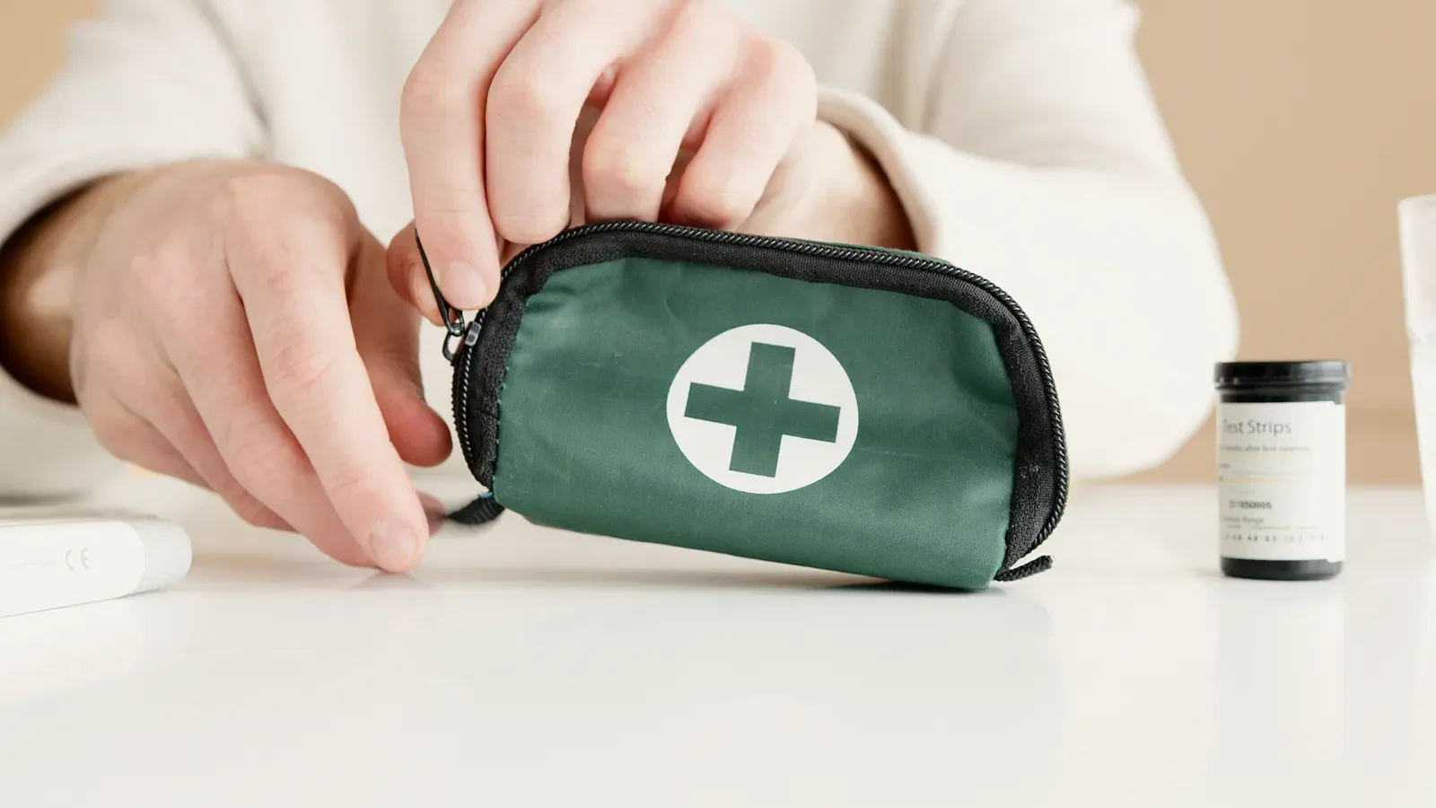 Hands opening a small green first aid kit pouch