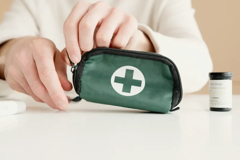 Hands opening a small green first aid kit pouch