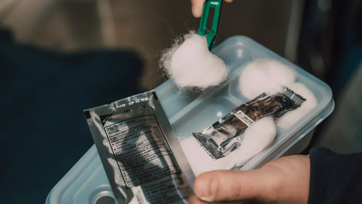 Hands organizing first aid supplies in a small container