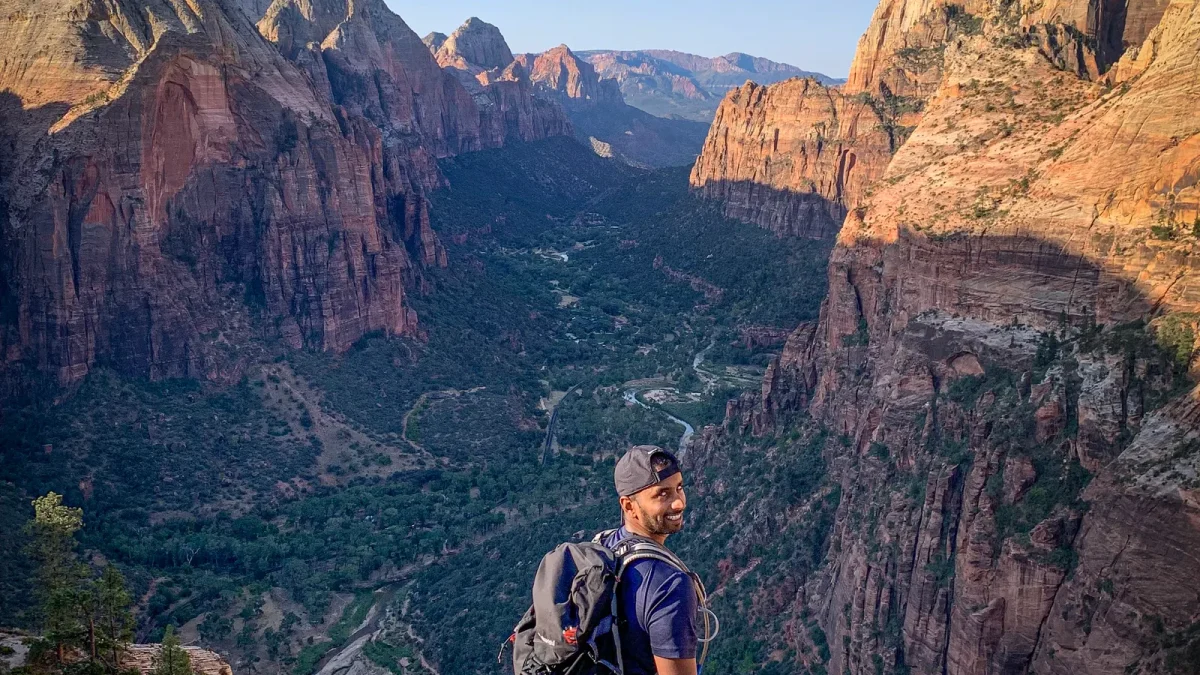 Hiker with a backpack looking out over a deep red-rock canyon