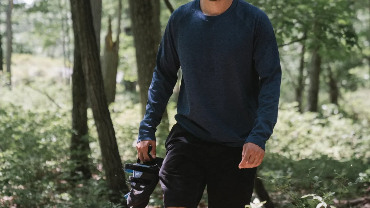 Hiker in a long-sleeve shirt walking through a forest