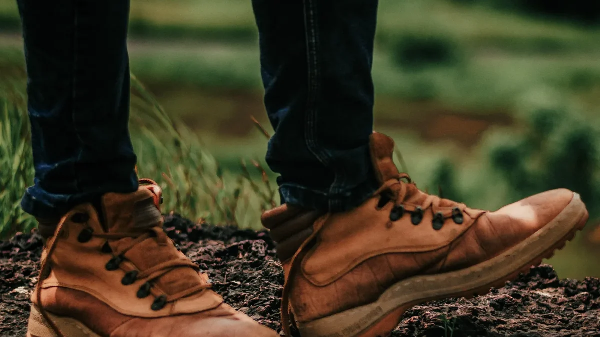 Close-up of brown leather hiking boots on a grassy trail