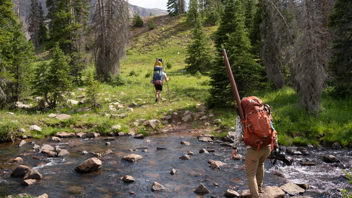 Backpacker stepping across a rocky stream in Utah’s Uinta National Forest