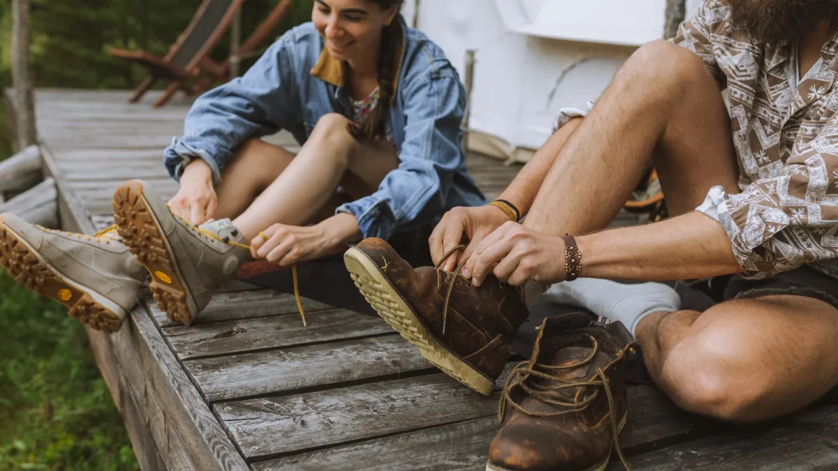 Two hikers sitting on a wooden deck tying their hiking boots