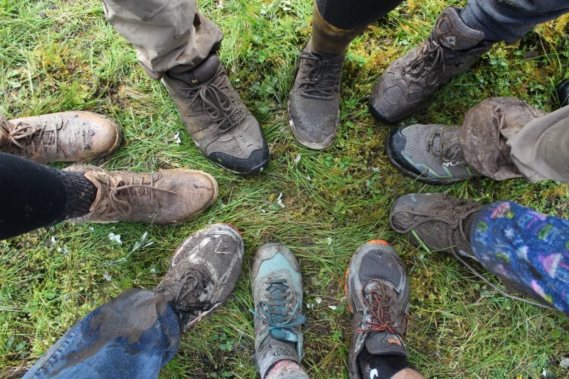 Circle of hikers' mud-caked boots on a trail