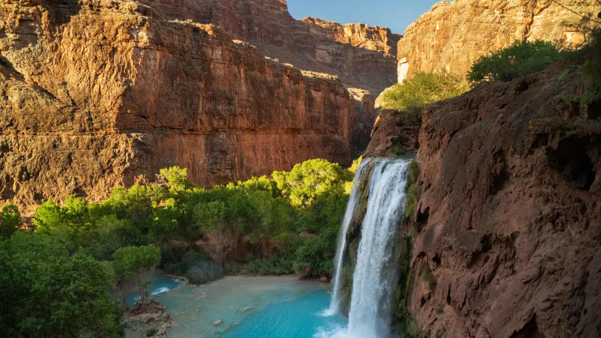 Havasu Falls plunging into a turquoise pool between red canyon walls