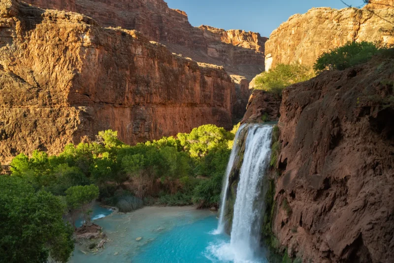 Havasu Falls plunging into a turquoise pool between red canyon walls