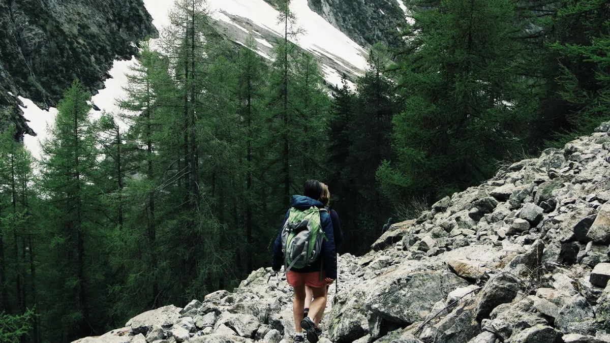 Backpacker hiking a rocky, snow-patched trail in Champoléon, France