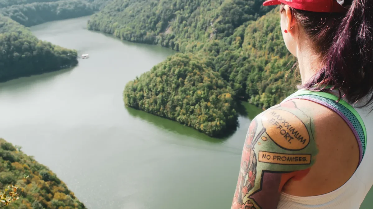 Close view of a hiker's bare shoulder in a tank top overlooking a lake