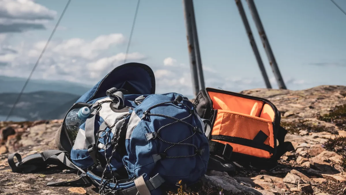 Two backpacks resting against a railing with a mountain view behind them
