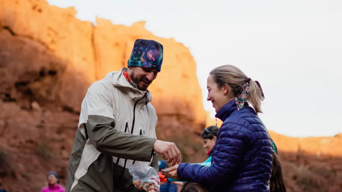 Two hikers exchanging trail snacks in a sunlit canyon