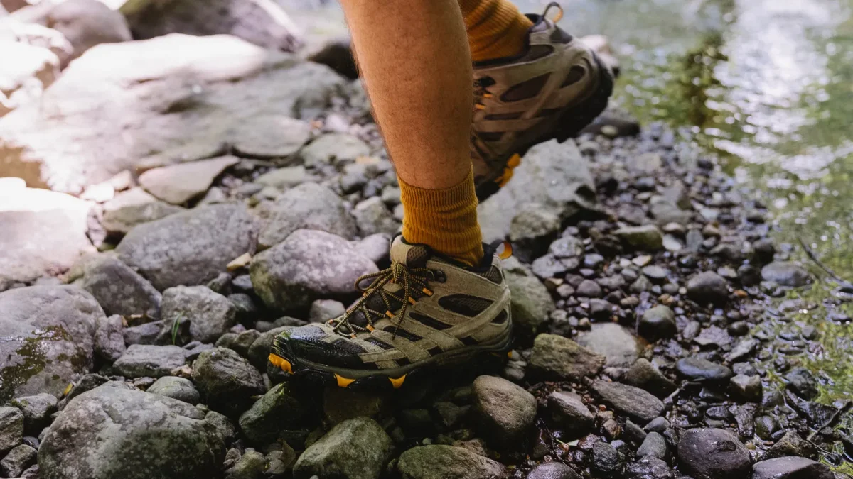 Close-up of hiking boots stepping over loose rocks on a streamside path